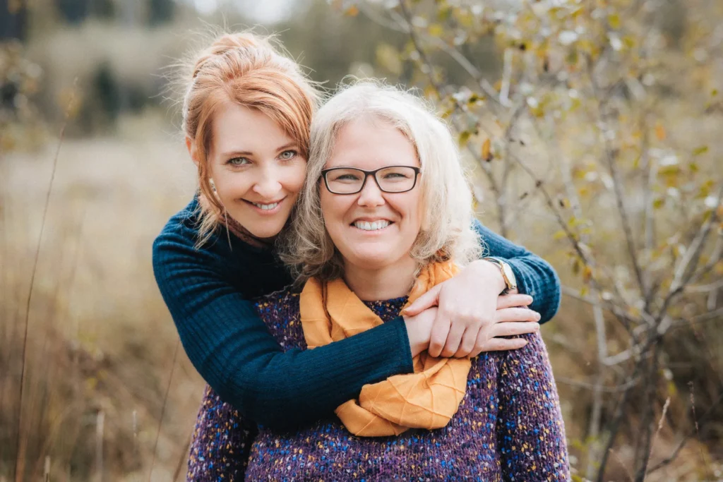 Zwei Frauen lächeln in herbstlicher Natur – emotionale Portraitaufnahme outdoor