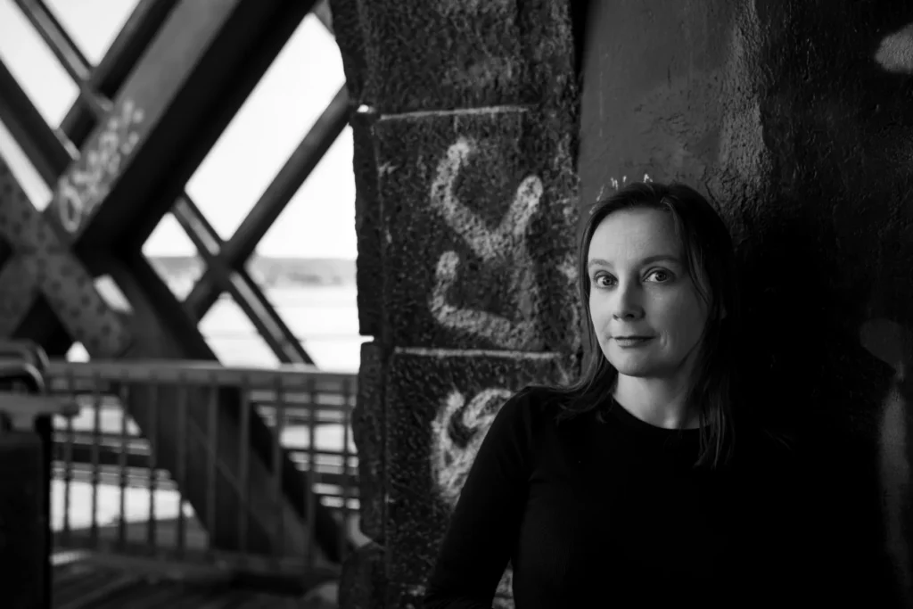 Portrait einer Frau vor einer strukturierten Wand mit Graffiti – Schwarzweißaufnahme